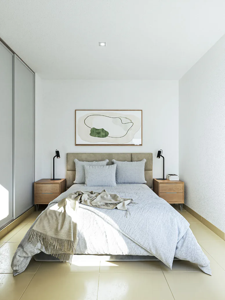 Dormitorio con cama doble de ropa blanca, mesas de luz de madera, un cuadro sobre la cabecera y placard de puertas corredizas