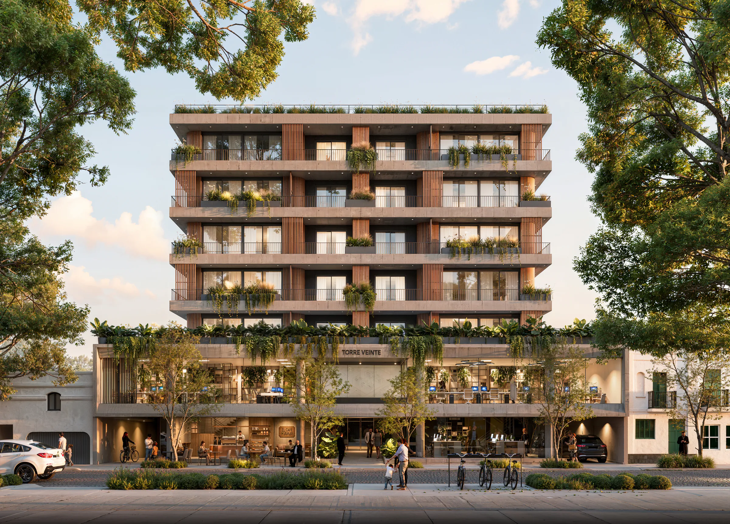 Fachada frontal de Torre Veinte sobre una calle adoquinada y arbolada: balcones de hormigón con listones de madera y jardineras, el cartel con el nombre sobre las oficinas vidriadas del primer piso y un café en planta baja, con luz de atardecer