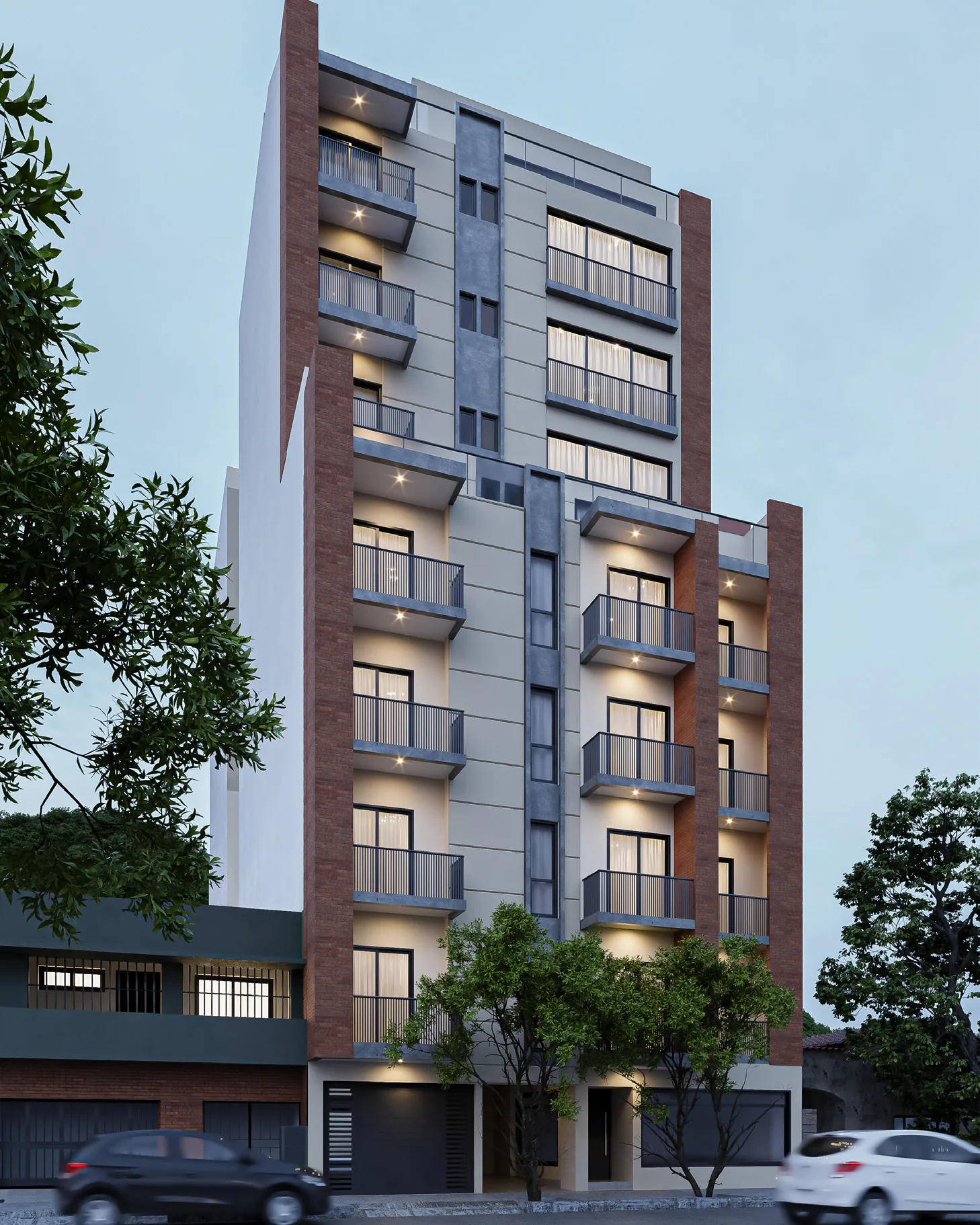 Render al anochecer de V954 desde la vereda de enfrente: edificio de balcones con barandas de vidrio, paños grises y pilastras de ladrillo, ventanas iluminadas, árboles en la vereda y autos estacionados