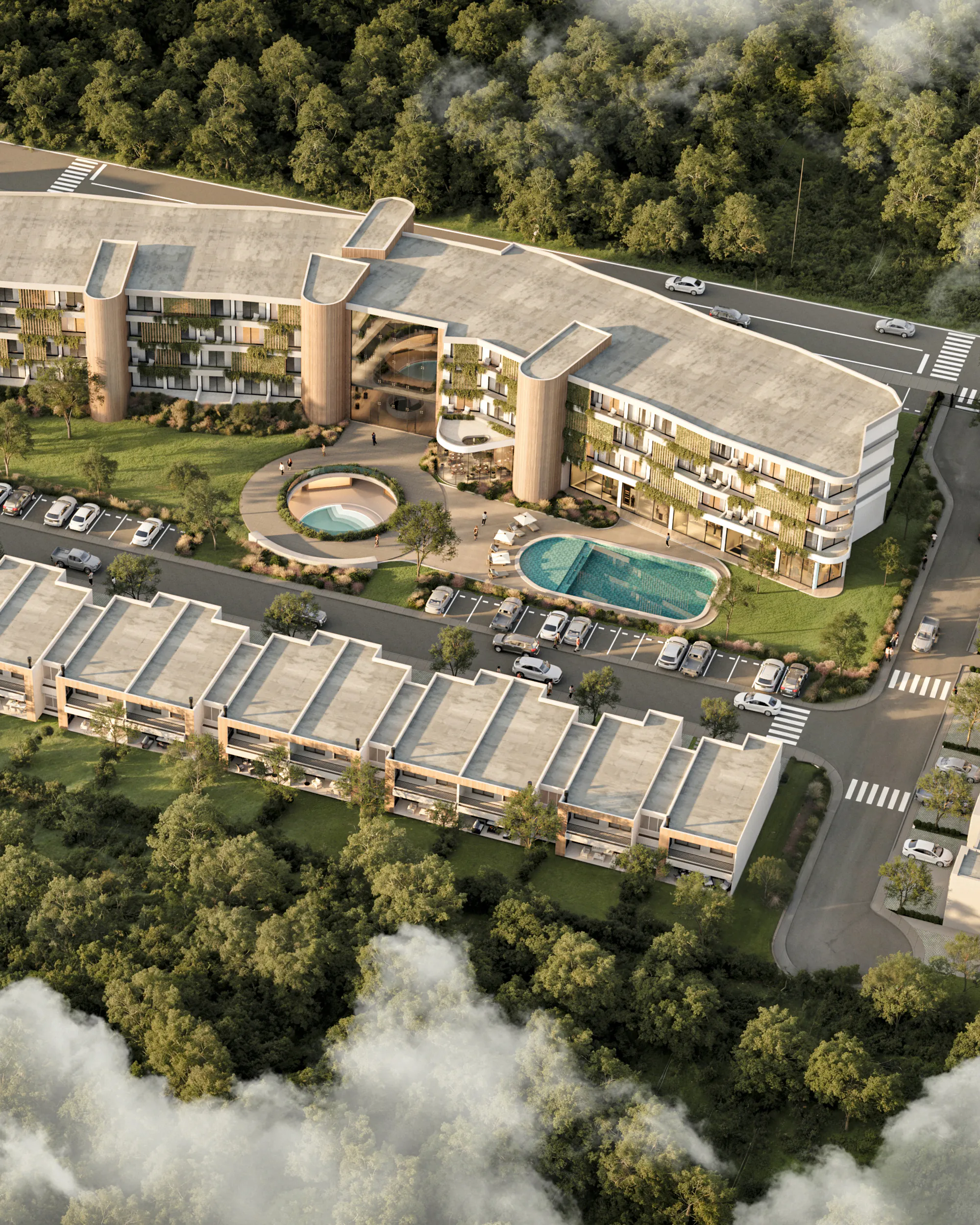 Vista aérea de un conjunto entre árboles y nubes: un edificio en curva de varios niveles con balcones y jardines, una pileta y un patio redondo en el centro, y filas de casas de dos plantas alrededor.